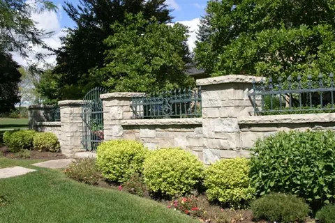 Limestone coping caps finishing a garden wall, with landscaping growing along its base