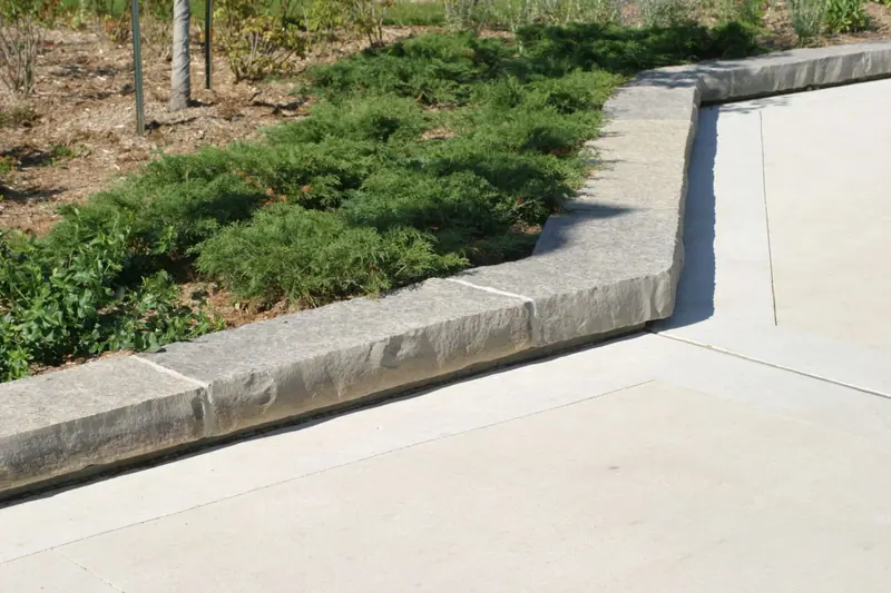 Limestone curbing separating a planting bed from a wide paved walkway