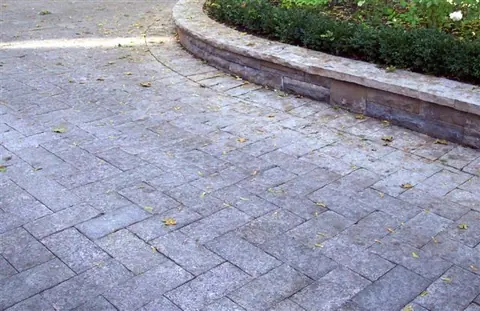 Limestone cobblestone paving curving past a low garden wall