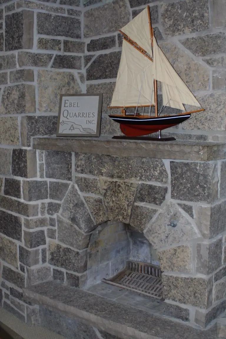 Limestone hearth and mantel with a coursed stone fireplace surround