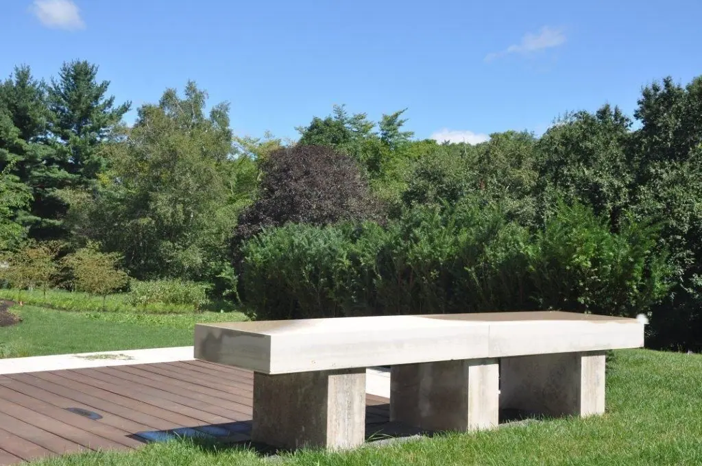 Sandblasted Algonquin limestone bench in a landscaped garden